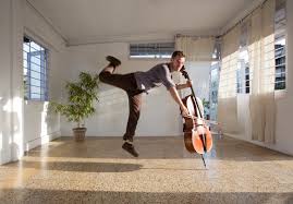 man leaping behind cello